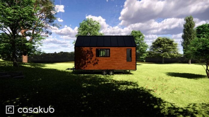 Vue arrière d'une tiny house en bois avec terrasse, située en pleine nature.